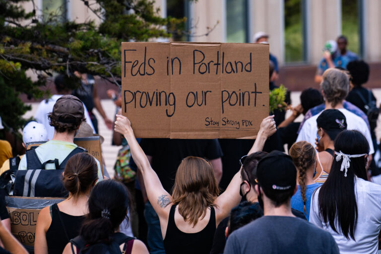 Feds in Portland proving our point 3 A woman holds up a sign that reads “Feds in Portland proving our point. Stay Strong PDX” outside the Federal Courthouse in downtown Minneapolis. Protesters gathered on July 23rd, 2020 to protest federal officers being deployed to cities around the country.