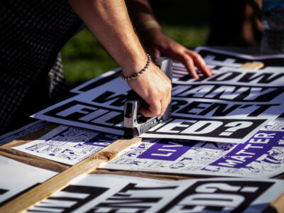 Stapling 'How many weren’t filmed?' signs, Uptown Minneapolis