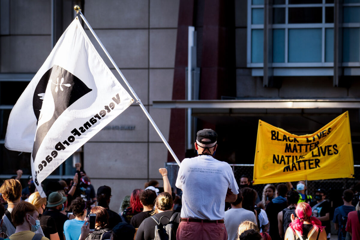 A veteran holds up a Veterans For Peace flag at a protest outside the Federal Courthouse in downtown Minneapolis. Protesters gathered on July 23rd, 2020 to protest federal officers being deployed to cities around the country.