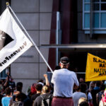 A veteran holds up a Veterans For Peace flag at a protest outside the Federal Courthouse in downtown Minneapolis. Protesters gathered on July 23rd, 2020 to protest federal officers being deployed to cities around the country.