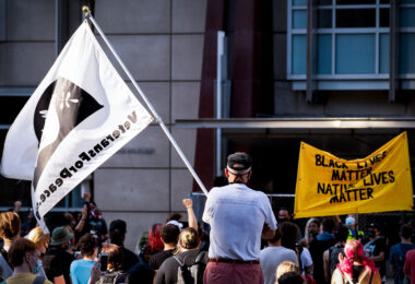 A veteran holds up a Veterans For Peace flag at a protest outside the Federal Courthouse in downtown Minneapolis. Protesters gathered on July 23rd, 2020 to protest federal officers being deployed to cities around the country.