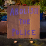 A sign that reads "Abolish the police" laying at the George Floyd Memorial in South Minneapolis.