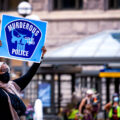 Woman holds up a sign that reads "Murderous Police" "City Of Lakes" at a protest and march in solidarity for Jacob Blake held in downtown Minneapolis at the Hennepin County Government Center.