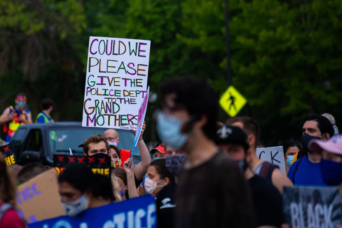 Students march at the Minnesota State Capitol. A protest holds a sign that reads “Could we please give the police dept to the grand mothers?”.