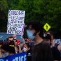 Students march at the Minnesota State Capitol. A protest holds a sign that reads “Could we please give the police dept to the grand mothers?”.