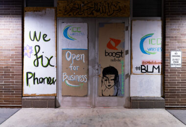 Cell phone store open for business with boards on the windows.