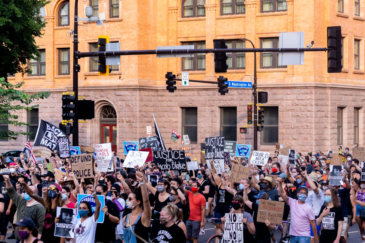 Protesters with signs march through downtown Minneapolis in solidarity with Jacob Blake after he was shot by Kenosha police.