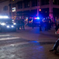 A homeless man sits on Nicollet Mall asking for help while riot police move in after rioting broke out following the false rumors of a downtown shooting by the police. The man died of a suicide.