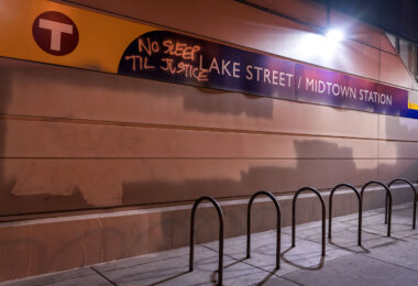 Graffiti reading No Sleep Til Justice on the Lake Street/Midtown Station signage in South Minneapolis.