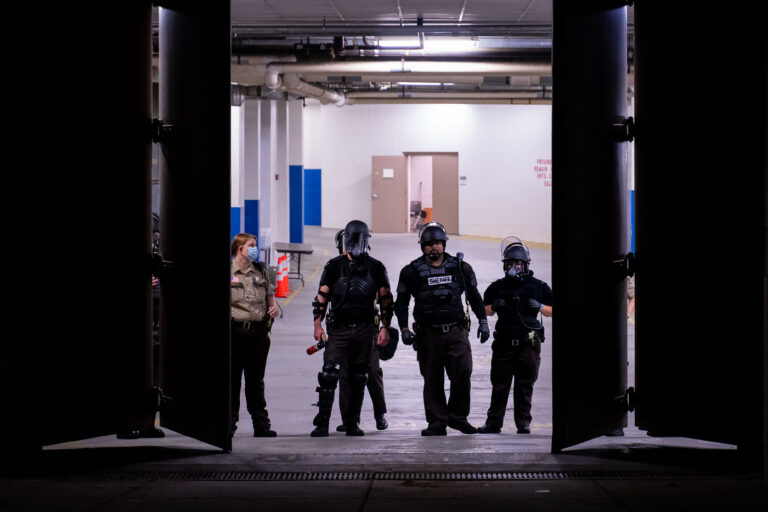 Officers in riot gear walk out of Downtown Minneapolis jail 3 Hennepin County Sheriffs Officers holding cans of irritants inside the garage of the Hennepin County Public Safety Facility, a downtown Minneapolis jail. Protesters were gathering demanding the release of other protesters who were arrested earlier in the evening after a protest through downtown in a Jacob Blake solidarity march.