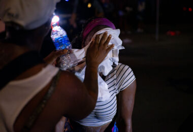 A man helps a woman who had been pepper sprayed by the Minneapolis Police following unrest that broke out over false rumors of a police shooting.