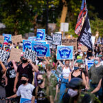 Protesters hold up Murderous Police signs in Downtown Minneapoli 1 Protesters march through downtown Minneapolis holding signs in solidarity with Jacob Blake after he was shot by Kenosha police.