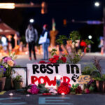 A memorial on Chicago Avenue in Minneapolis near the location of George Floyd's death with lit candles. A sign reads “Rest In Power”.