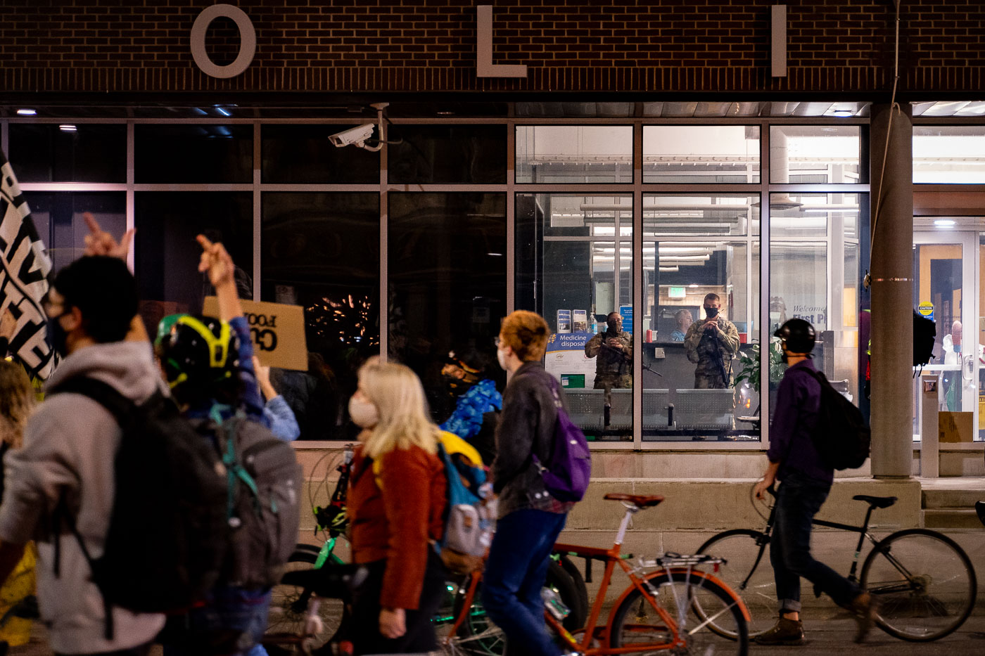 Protesters walk by the 1st precinct police station