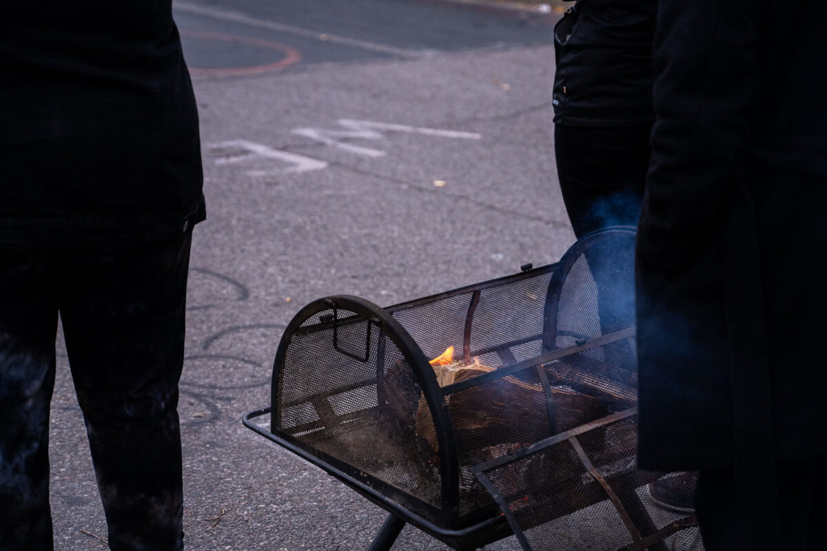 Those at the square keep themselves warm with a fire.