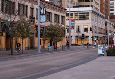 Bikers bike past boarded up buildings on Nicollet Mall in Downtown Minneapolis.