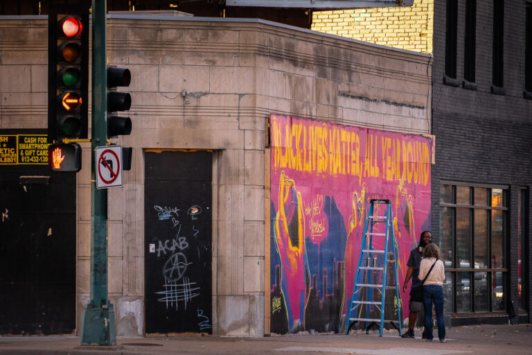Black Lives Matter mural being painted on Lyndale 1 An artist stops to talk with someone as he paints a mural on Lyndale Avenue storefront boards.