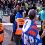 Protesters gather outside of the Minneapolis Police Third Precinct as part of a march shortly after Biden won the Presidential election. Protesters wearing orange vests that read “Democracy Defender”.