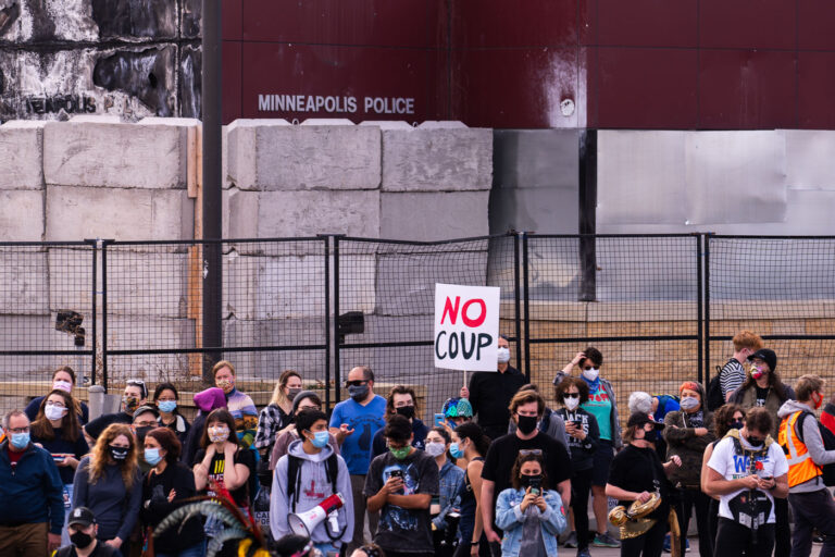 Protester holds up No Coup sign in front of police station 1 Protesters gather outside of the Minneapolis Police Third Precinct as part of a march shortly after Biden was announced as winner of the Presidential election.