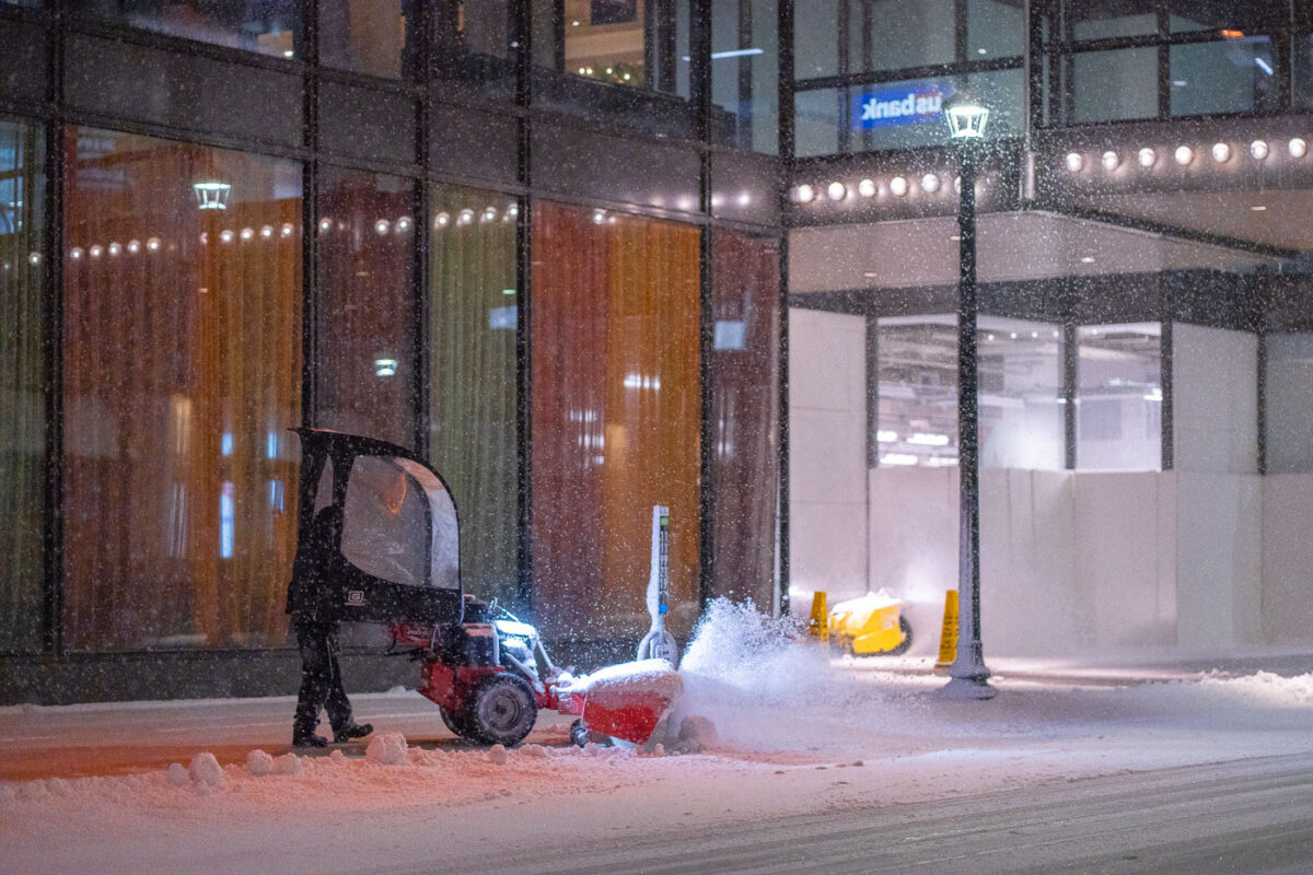 A man plows the snow off a sidewalk in downtown Minneapolis on November 11th, 2020