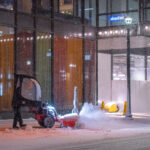 A man plows the snow off a sidewalk in downtown Minneapolis on November 11th, 2020