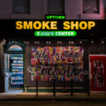 Uptown Smoke Shop with boards that read “Help + Love each other”