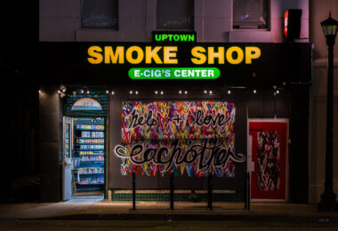 Uptown Smoke Shop with boards that read “Help + Love each other”