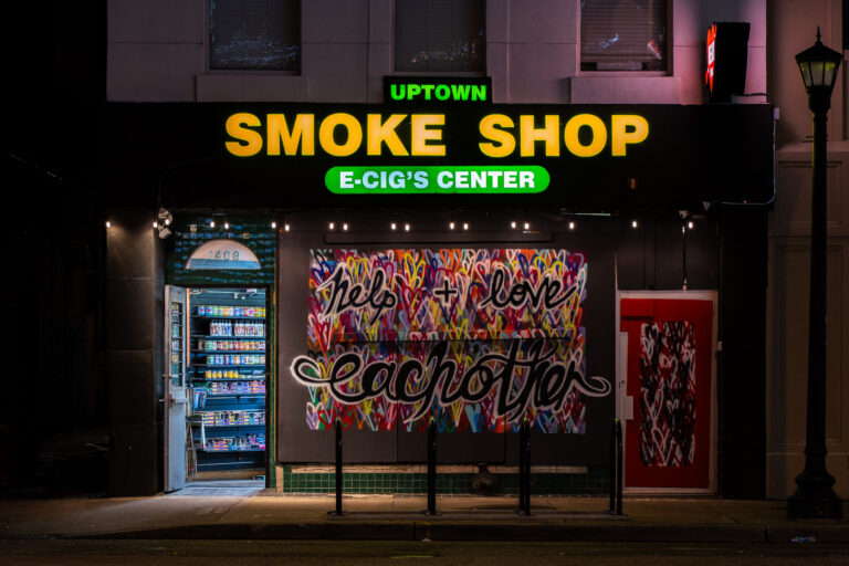 Uptown Smoke Shop 2 Uptown Smoke Shop with boards that read “Help + Love each other”