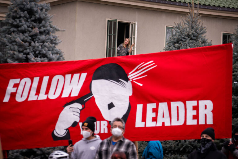 Follow Your Leader in St. Paul 2 A woman looks out her window at dueling protests occurring across the street at the Governor's Residence. For weeks Stop The Steal protesters have been gathering outside the Governor’s mansion.