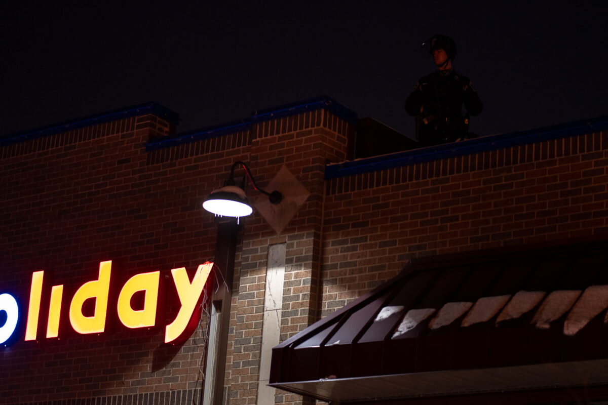 Minneapolis Police on the roof of the Holiday gas station as protesters gather outside where Minneapolis police shot and killed Dolal Idd.
