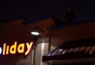 Minneapolis Police on the roof of the Holiday gas station as protesters gather outside where Minneapolis police shot and killed Dolal Idd.