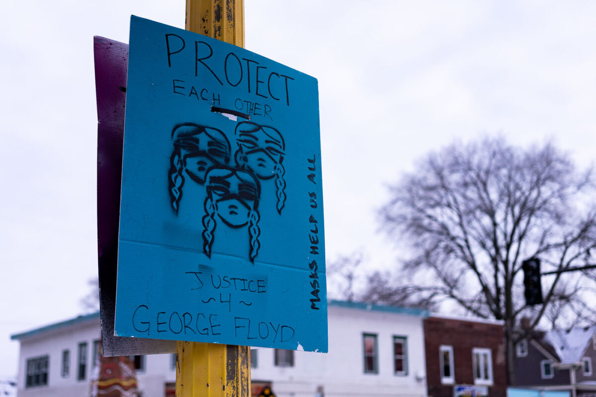A sign at George Floyd Square that reads "Protect Each Other" "Justice 4 George Floyd" "Masks Help Us All"