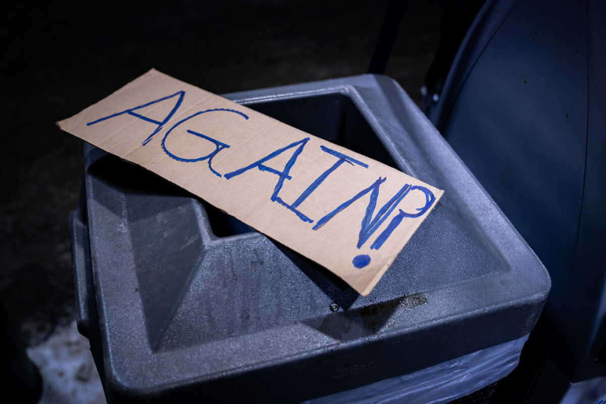 A protest sign reading "AGAIN?" sits at a vigil for Dolal Idd who was killed by the Minneapolis Police on December 30th.