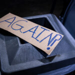 A protest sign reading "AGAIN?" sits at a vigil for Dolal Idd who was killed by the Minneapolis Police on December 30th.