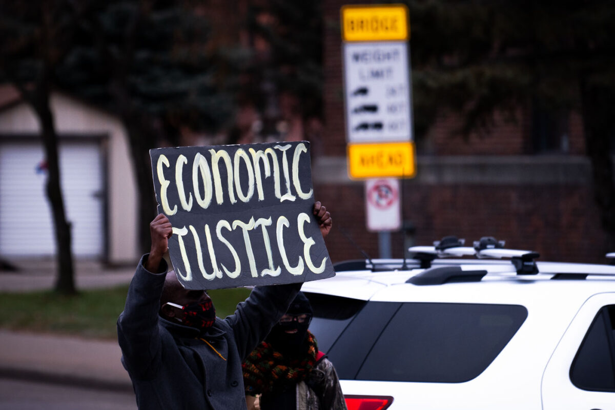 Protester holds up a sign that reads "Economic Justice" during a defund police rally.