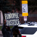 Protester holds up a sign that reads "Economic Justice" during a defund police rally.