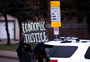 Protester holds up a sign that reads "Economic Justice" during a defund police rally.