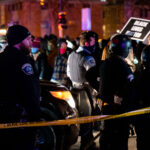 Minneapolis police surround the Holiday Gas station where Dolal Idd was shot and killed as protesters gather.