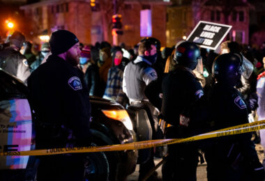 Minneapolis police surround the Holiday Gas station where Dolal Idd was shot and killed as protesters gather.