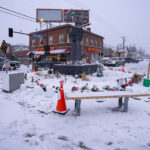 Snow falls over the metal fist at George Floyd Square.