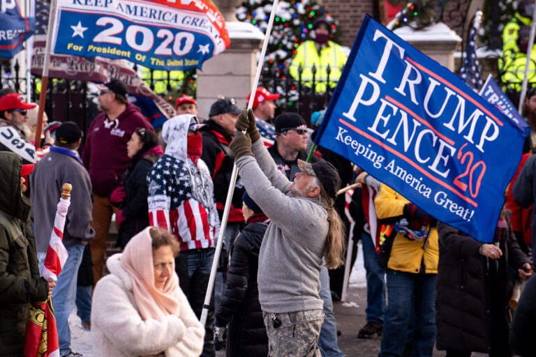 Man holds a large flag at a Stop The Steal Protest 3 Trump supporters gather at the Minnesota Governor’s Residence after a “Storm The Capitol” event at the Minnesota State Capitol.