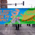 Protesters march in St. Paul holding up a sign reading "We want soup for my family and yours".