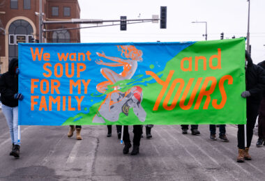Protesters march in St. Paul holding up a sign reading "We want soup for my family and yours".