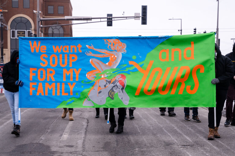 We want soup for my family and yours 4 Protesters march in St. Paul holding up a sign reading "We want soup for my family and yours".