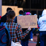 A woman holds a sign at a press conference announcing a March 8th protest at the start of the Derek Chauvin trial.