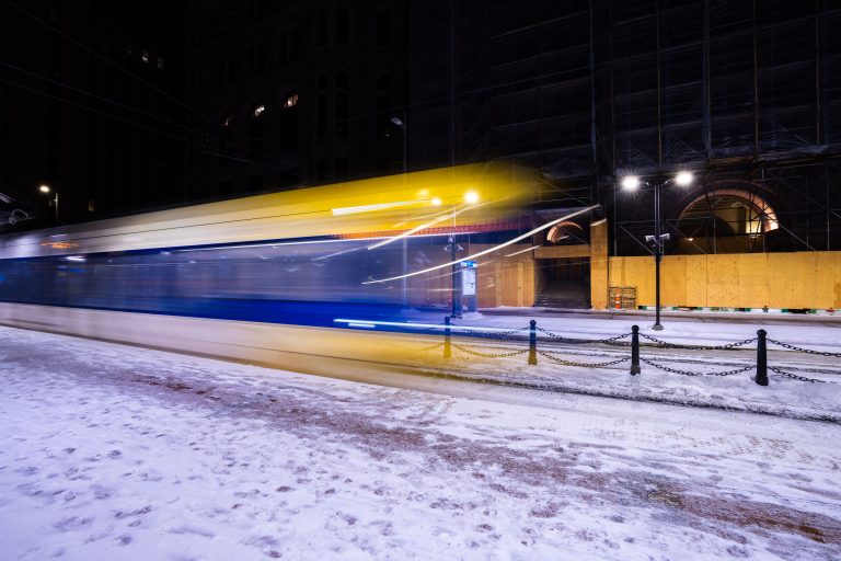 Light Rail Passing Minneapolis City Hall Under Renovation 1 Light rail train passing scaffolded Minneapolis City Hall building in downtown Minneapolis at night.