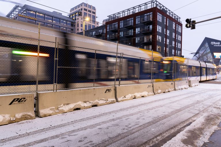 Metro Transit Light Rail Near US Bank Stadium, Minneapolis 2 A Metro Transit light rail train passes downtown Minneapolis buildings near US Bank Stadium on a snowy street.