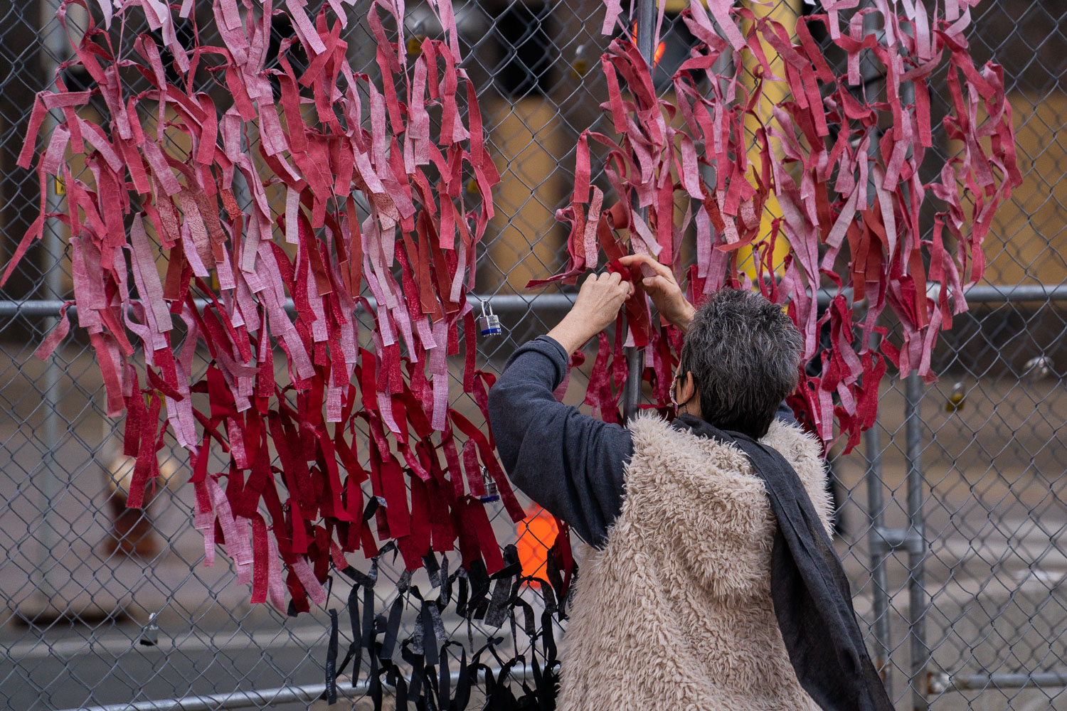 March 29, 2021 - Minneapolis -- A woman ties ribbons in the shape of a heart to security fencing around the Hennepin County Government Center on the day opening statements began in the Derek Chauvin murder trial. Chauvin is accused of murdering George Floyd on May 25th, 2020.