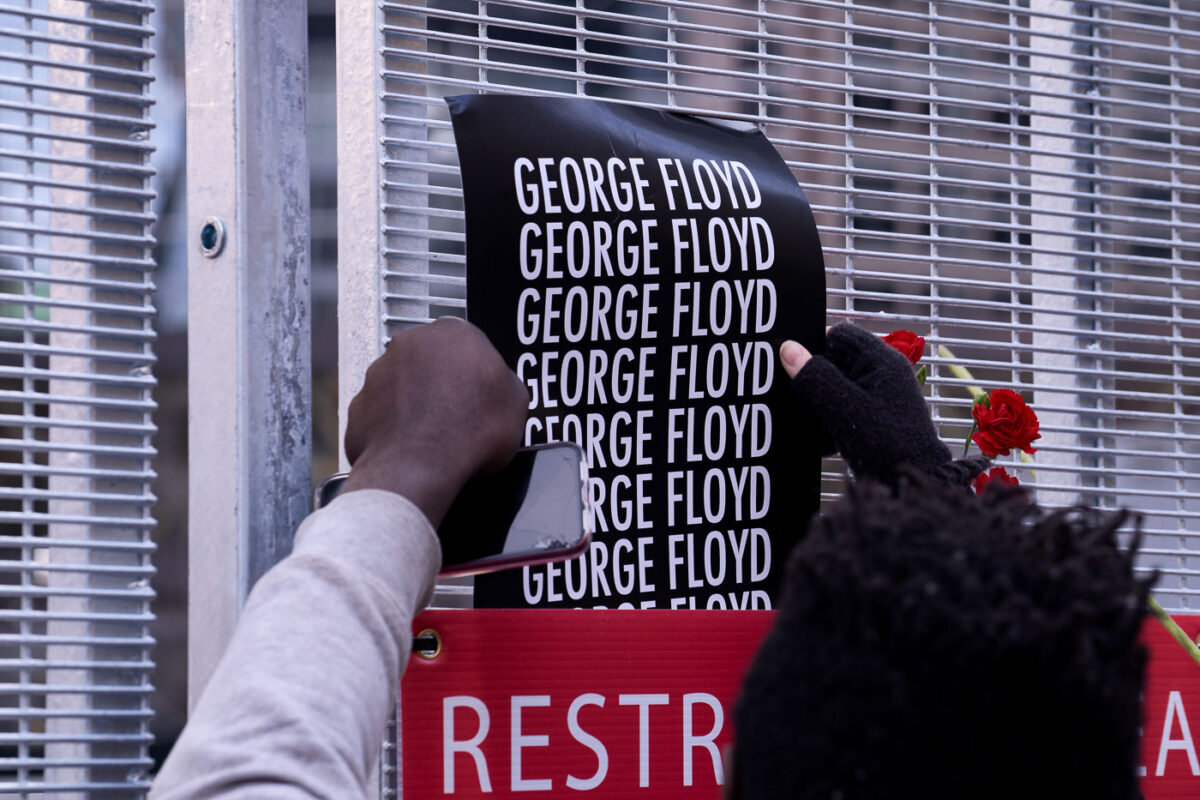 A protester puts a George Floyd poster on security fencing at the Hennepin County Government Center, where the Derek Chauvin murder trial is being held.