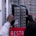 A protester puts a George Floyd poster on security fencing at the Hennepin County Government Center, where the Derek Chauvin murder trial is being held.